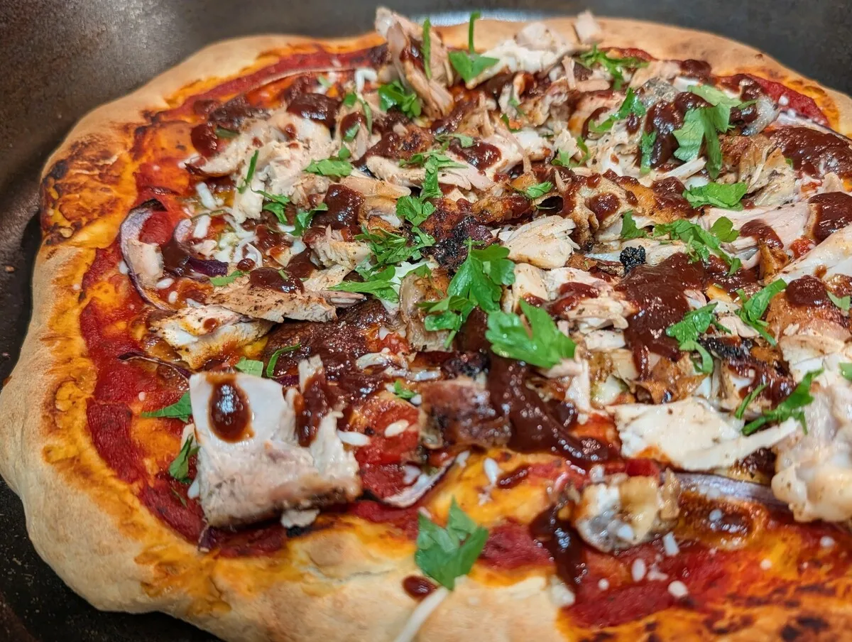 Cast iron skillet pizza with pulled chicken, mozzarella, and fresh herbs